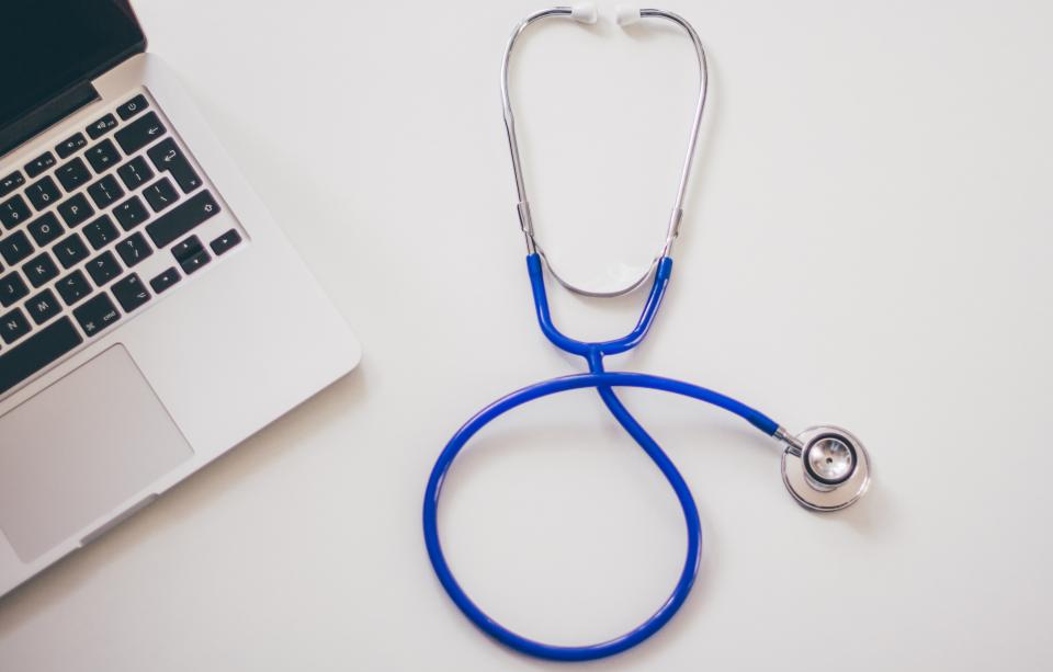 Estetoscopio médico sobre escritorio con ordenador, contexto de consulta médica